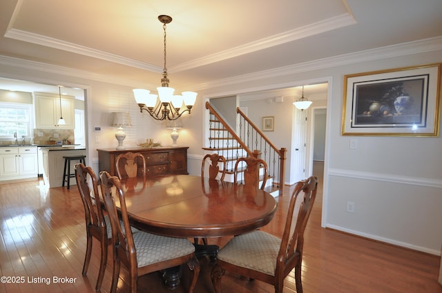 dining area with hardwood / wood-style floors, stairway, an inviting chandelier, and baseboards