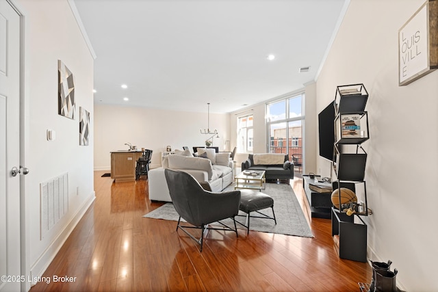 living room with baseboards, visible vents, ornamental molding, wood finished floors, and recessed lighting