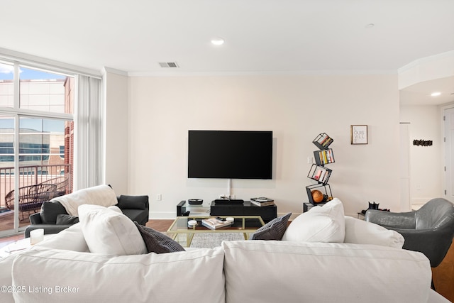 living area featuring visible vents, crown molding, baseboards, and wood finished floors