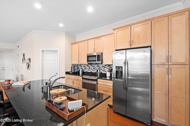 kitchen featuring light brown cabinets, stainless steel appliances, a sink, decorative backsplash, and dark stone counters