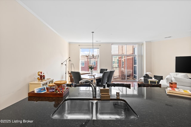 kitchen with a notable chandelier, a sink, open floor plan, hanging light fixtures, and dark countertops