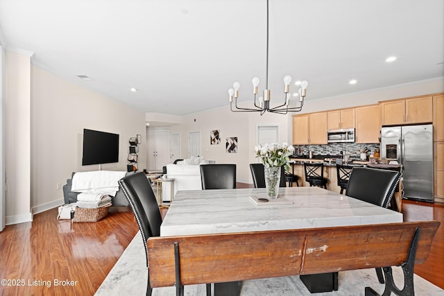 dining space with recessed lighting, light wood-style flooring, baseboards, and an inviting chandelier