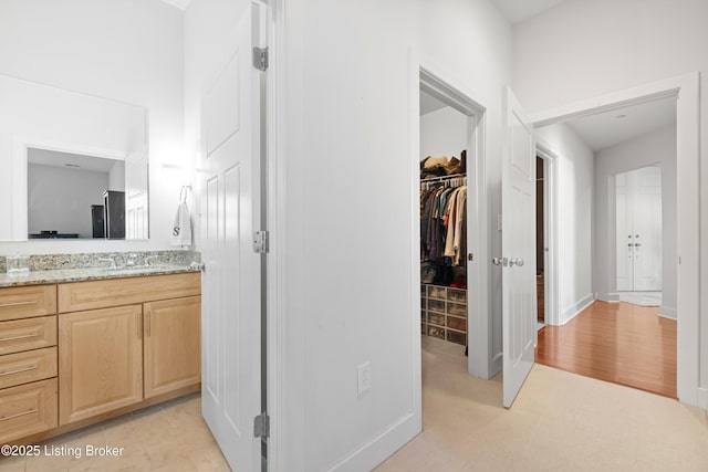 bathroom featuring a spacious closet and vanity