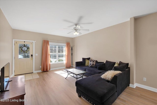 living area with baseboards, ceiling fan, and light wood-style floors