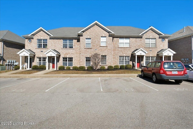 townhome / multi-family property with uncovered parking and brick siding