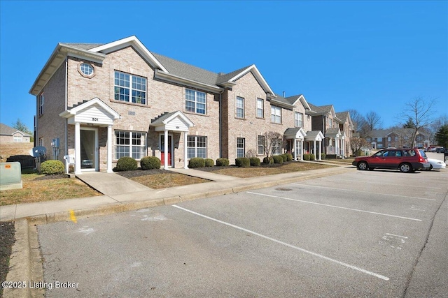 multi unit property featuring uncovered parking, a residential view, and brick siding