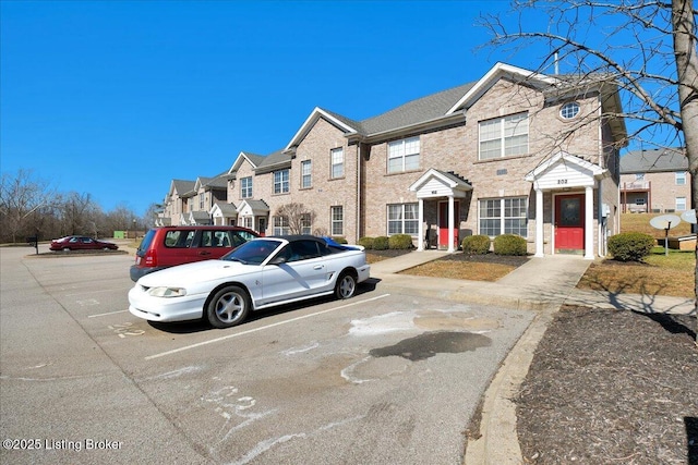 townhome / multi-family property featuring uncovered parking and brick siding