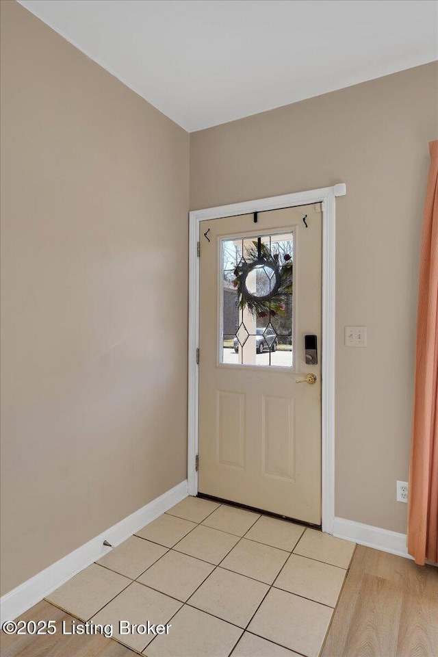 doorway to outside featuring light tile patterned floors and baseboards