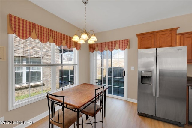 dining space with light wood finished floors, baseboards, and a chandelier