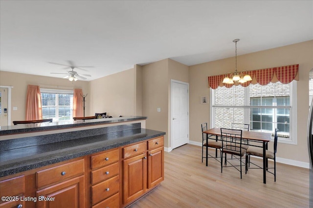 kitchen featuring brown cabinetry, baseboards, hanging light fixtures, and light wood finished floors