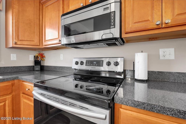 kitchen featuring appliances with stainless steel finishes, dark countertops, and brown cabinets