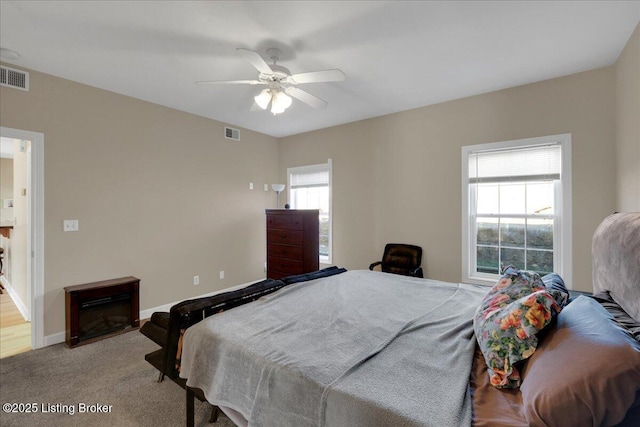 carpeted bedroom featuring baseboards, a fireplace, visible vents, and a ceiling fan