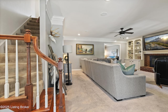 living area featuring carpet floors, a ceiling fan, ornamental molding, stairway, and a brick fireplace