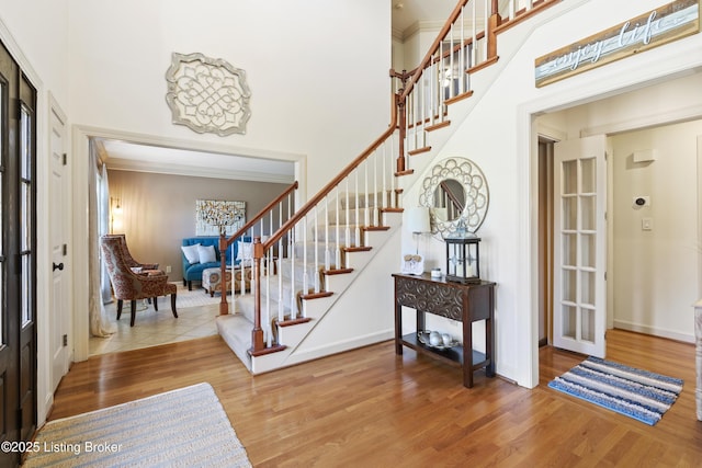 entrance foyer with baseboards, stairway, a high ceiling, and wood finished floors