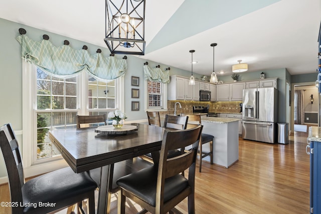 dining area with vaulted ceiling and light wood finished floors