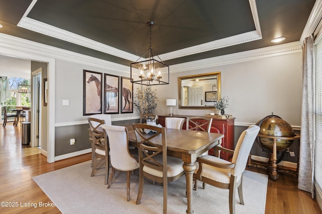 dining area with a chandelier, wood finished floors, baseboards, ornamental molding, and a tray ceiling