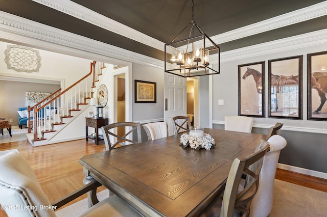 dining room featuring crown molding, stairway, an inviting chandelier, wood finished floors, and baseboards