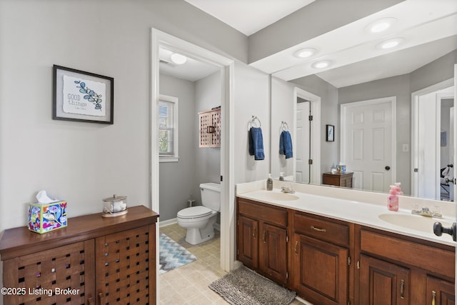 full bathroom with double vanity, toilet, and a sink