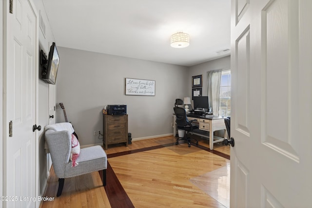 office area with light wood finished floors, visible vents, and baseboards