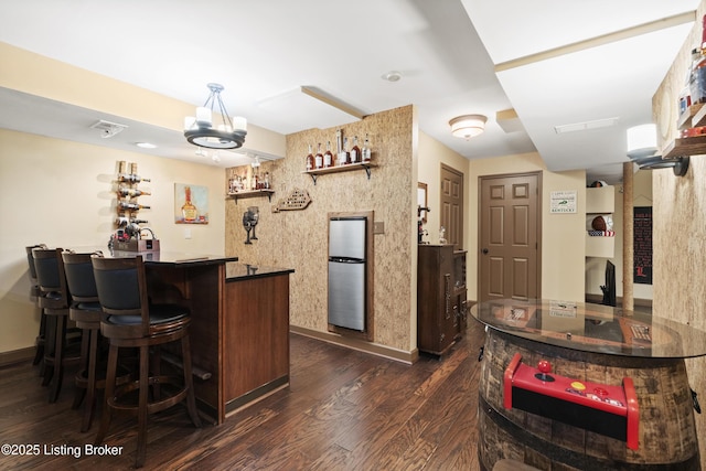 bar featuring visible vents, baseboards, a bar, dark wood finished floors, and an inviting chandelier