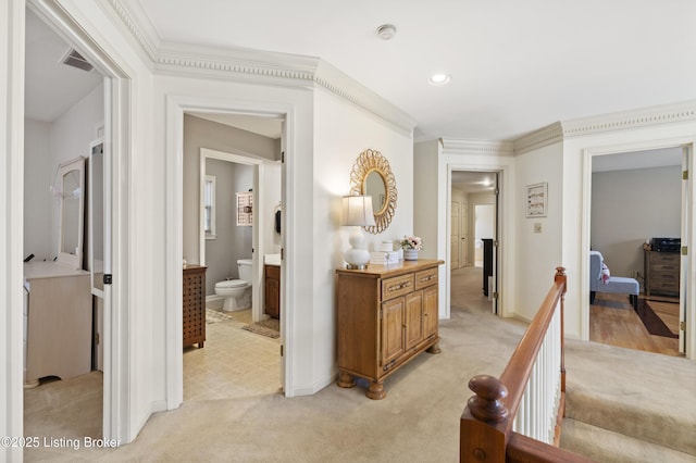 hall with light carpet, crown molding, visible vents, and an upstairs landing