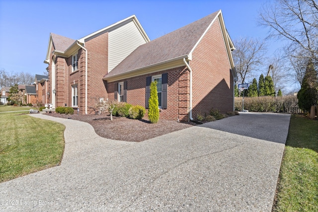 view of home's exterior featuring a yard, concrete driveway, brick siding, and a shingled roof