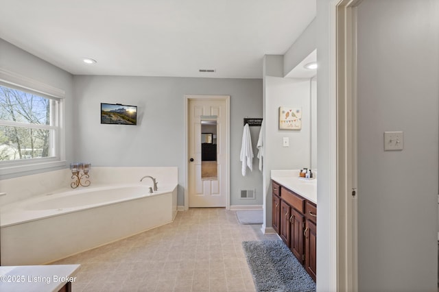 bathroom featuring a garden tub, baseboards, visible vents, and vanity