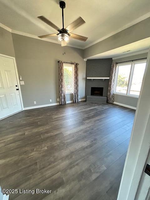 unfurnished living room featuring dark wood-type flooring, plenty of natural light, and ornamental molding