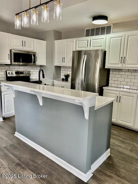 kitchen featuring dark wood-style flooring, light countertops, visible vents, and appliances with stainless steel finishes