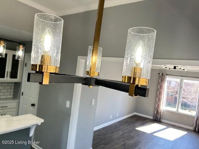 interior space featuring baseboards, crown molding, decorative backsplash, and wood finished floors