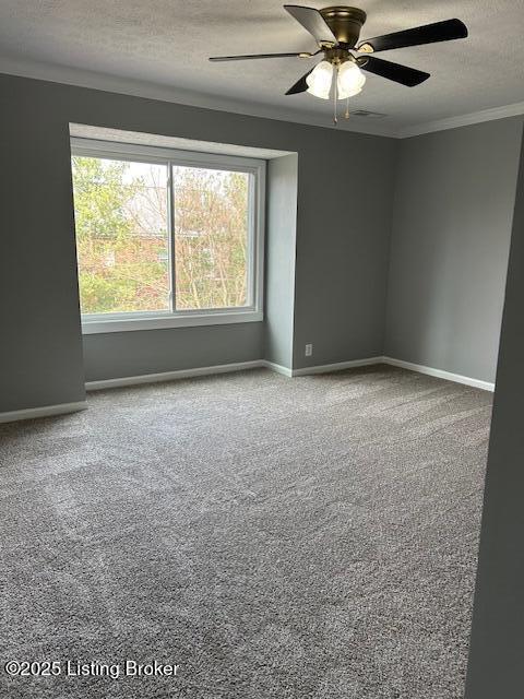 empty room with a textured ceiling, crown molding, baseboards, and carpet floors