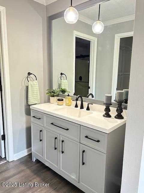 bathroom with ornamental molding, wood finished floors, vanity, and baseboards