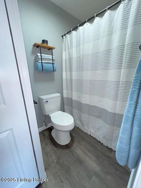 full bathroom with curtained shower, toilet, wood finished floors, and baseboards