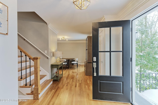 foyer entrance featuring stairs, baseboards, light wood-style flooring, and crown molding