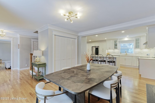 dining space featuring an inviting chandelier, ornamental molding, and light wood-style floors