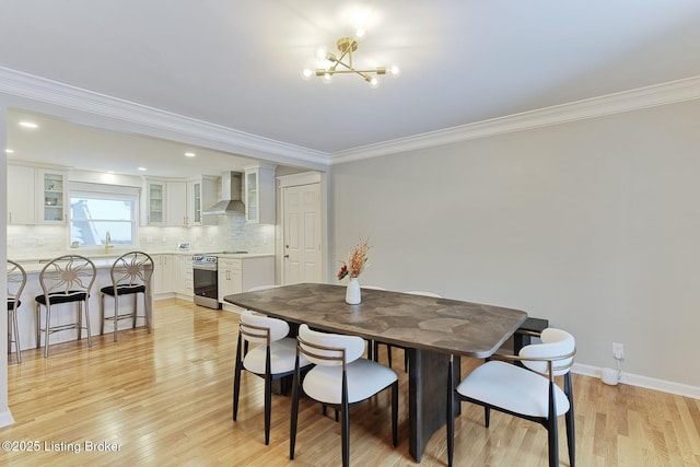 dining area with crown molding, a notable chandelier, and light wood finished floors