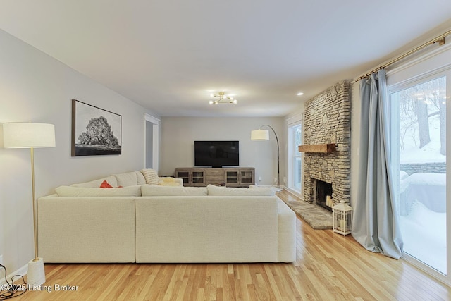 living area featuring a stone fireplace and light wood-type flooring