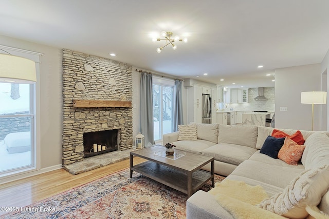 living area featuring baseboards, light wood-type flooring, a fireplace, and recessed lighting