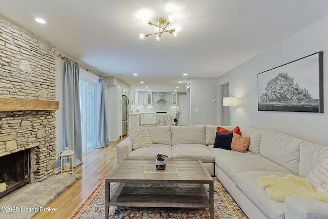 living room featuring light wood finished floors, recessed lighting, and a stone fireplace