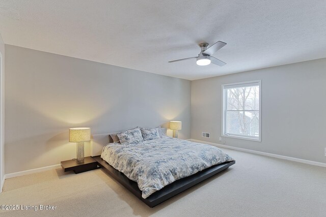 carpeted bedroom with visible vents, ceiling fan, a textured ceiling, and baseboards