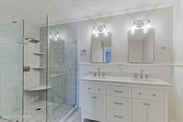 bathroom featuring a tile shower, wainscoting, and a sink