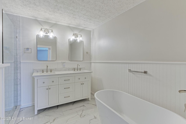 bathroom with marble finish floor, double vanity, wainscoting, and a sink