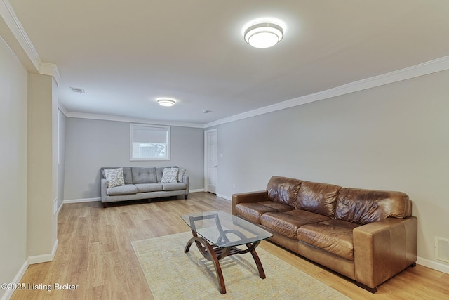 living room with baseboards, ornamental molding, visible vents, and light wood-style floors