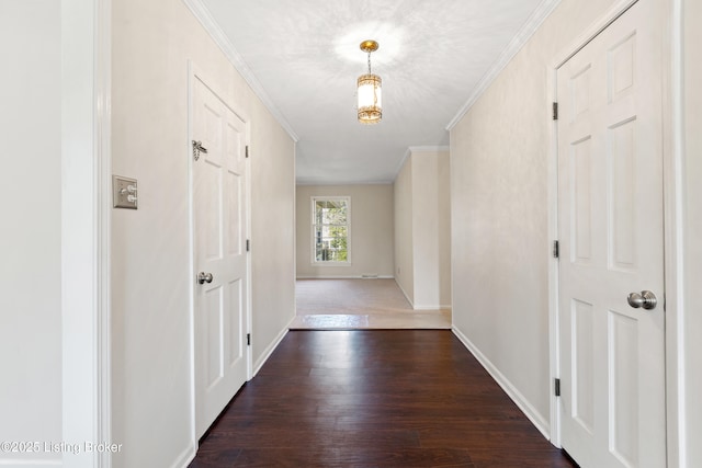 hall featuring dark wood-style floors, baseboards, and crown molding