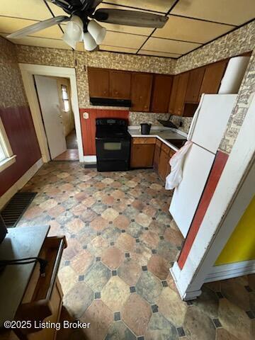 kitchen featuring electric range, visible vents, light countertops, ventilation hood, and freestanding refrigerator