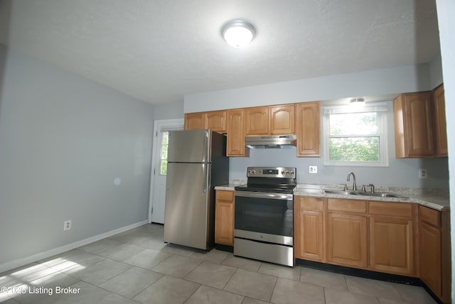 kitchen featuring baseboards, appliances with stainless steel finishes, a textured ceiling, under cabinet range hood, and a sink