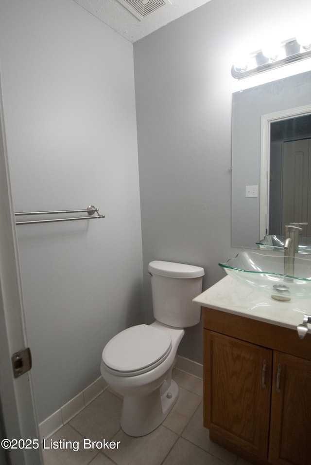 half bathroom featuring toilet, tile patterned flooring, visible vents, and vanity