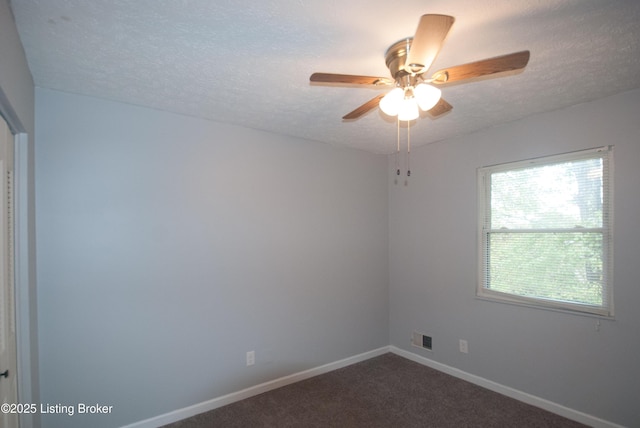 empty room with a textured ceiling, a ceiling fan, visible vents, baseboards, and dark colored carpet