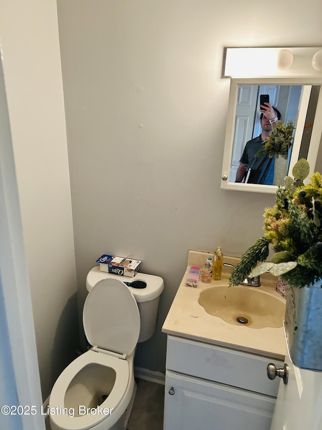 half bathroom featuring baseboards, vanity, and toilet