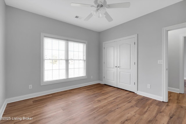 unfurnished bedroom with a closet, visible vents, a ceiling fan, light wood-type flooring, and baseboards